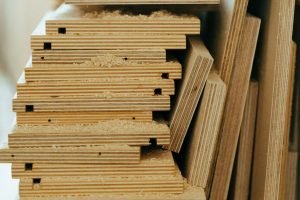 Close-up of stacked plywood sheets in a workshop, showcasing woodworking materials and textures.
